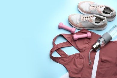 Sportswear, water bottle and dumbbells on light blue background, above view with space for text. Gym workout