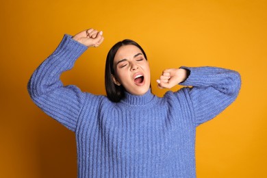 Young tired woman yawning on yellow background