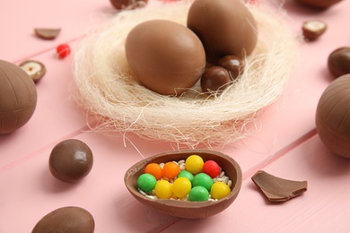 Delicious chocolate Easter eggs and candies on pink wooden table