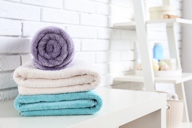 Stack of fresh towels on table in bathroom. Space for text