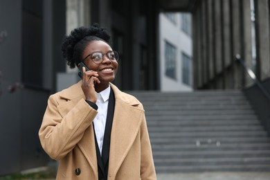 Photo of Happy woman talking on smartphone outdoors, space for text. Lawyer, businesswoman, accountant or manager