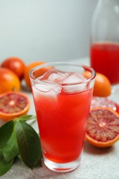 Photo of Tasty sicilian orange juice with ice cubes in glass and fruits on light grey table