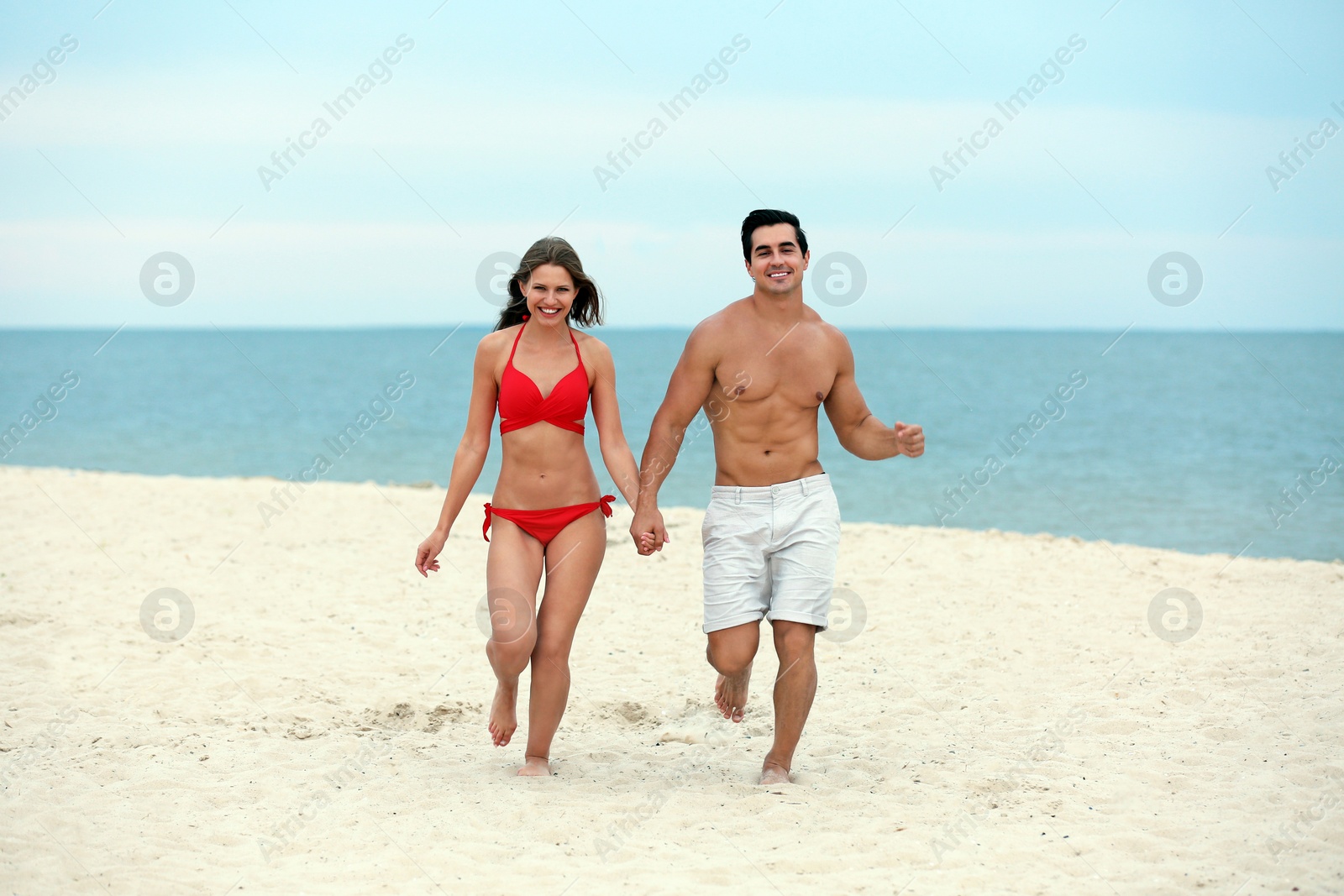 Photo of Happy young couple running together on sea beach