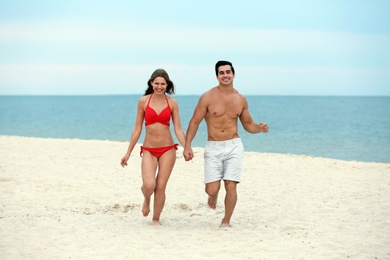 Happy young couple running together on sea beach