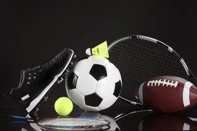 Many different sports equipment on black mirror surface