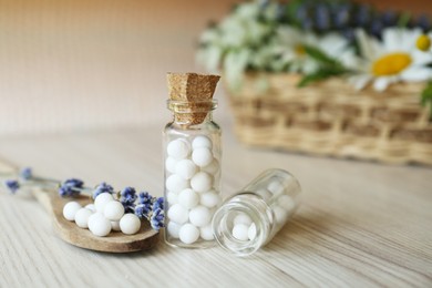 Photo of Bottles with homeopathic remedy and flowers on wooden table, closeup