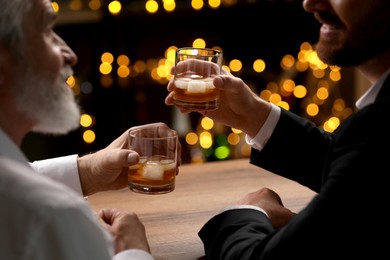 Photo of Men with glasses of whiskey talking at wooden table in bar