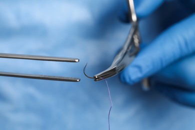 Photo of Professional surgeon holding forceps with suture thread, closeup. Medical equipment