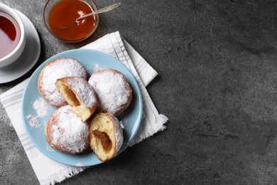 Delicious sweet buns with jam and cup of tea on gray table, flat lay. Space for text