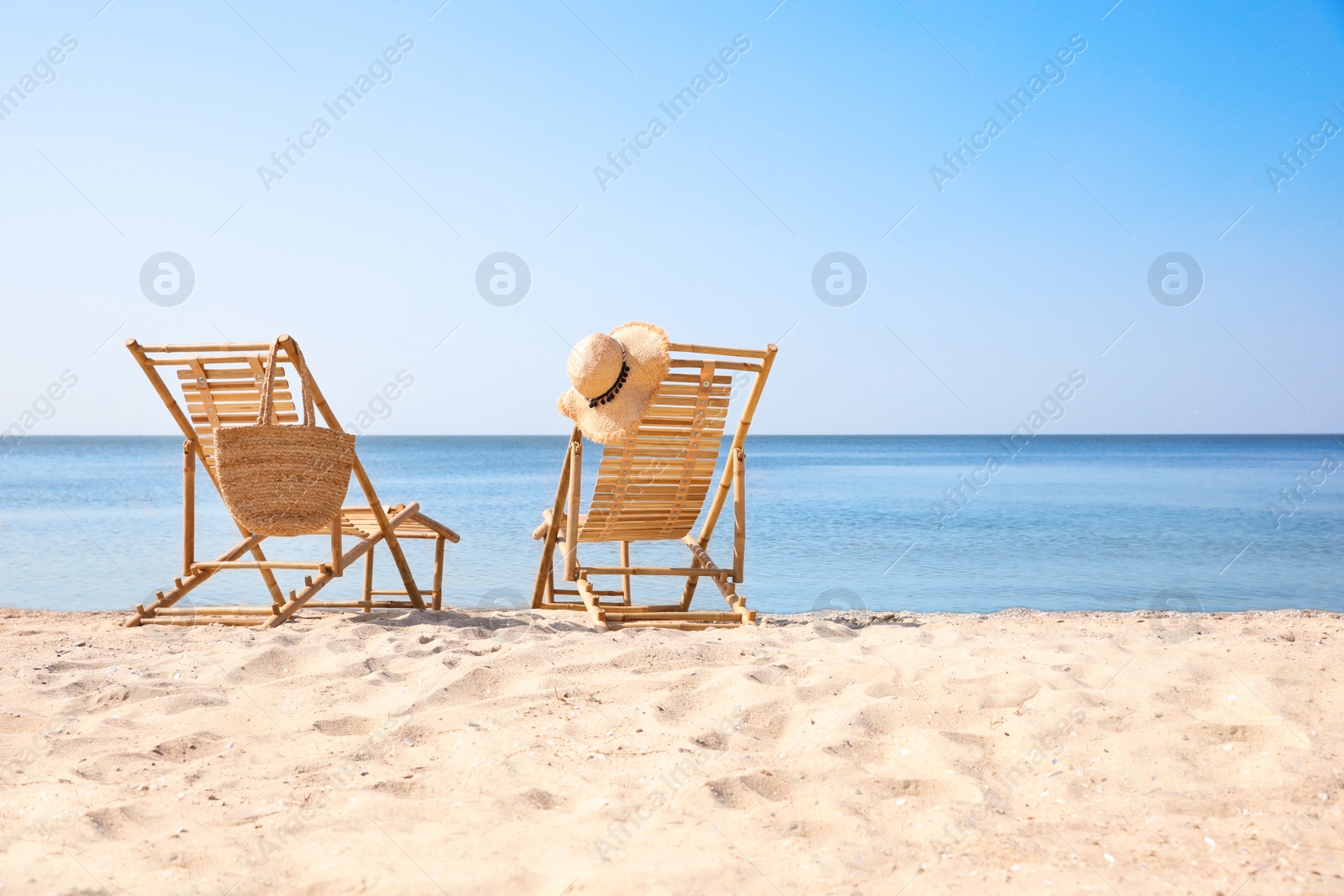 Photo of Wooden deck chairs on sandy beach near sea