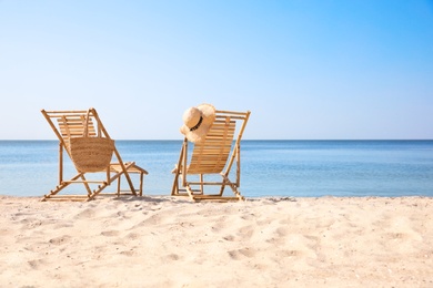 Photo of Wooden deck chairs on sandy beach near sea