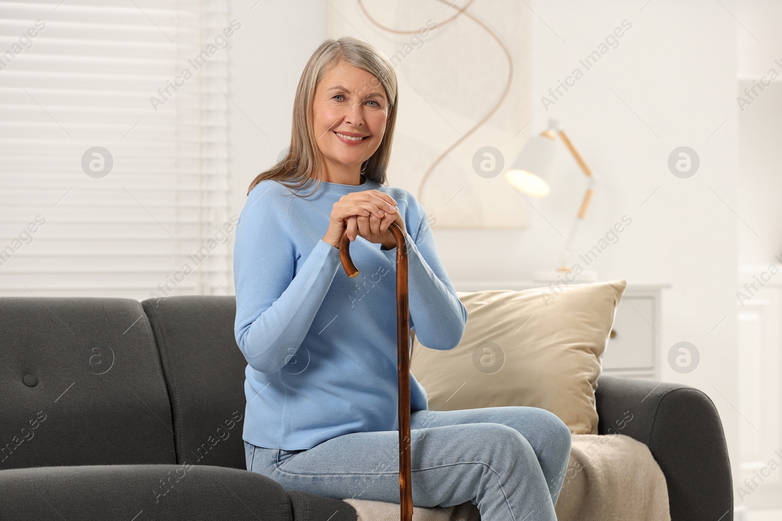 Photo of Mature woman with walking cane on sofa at home