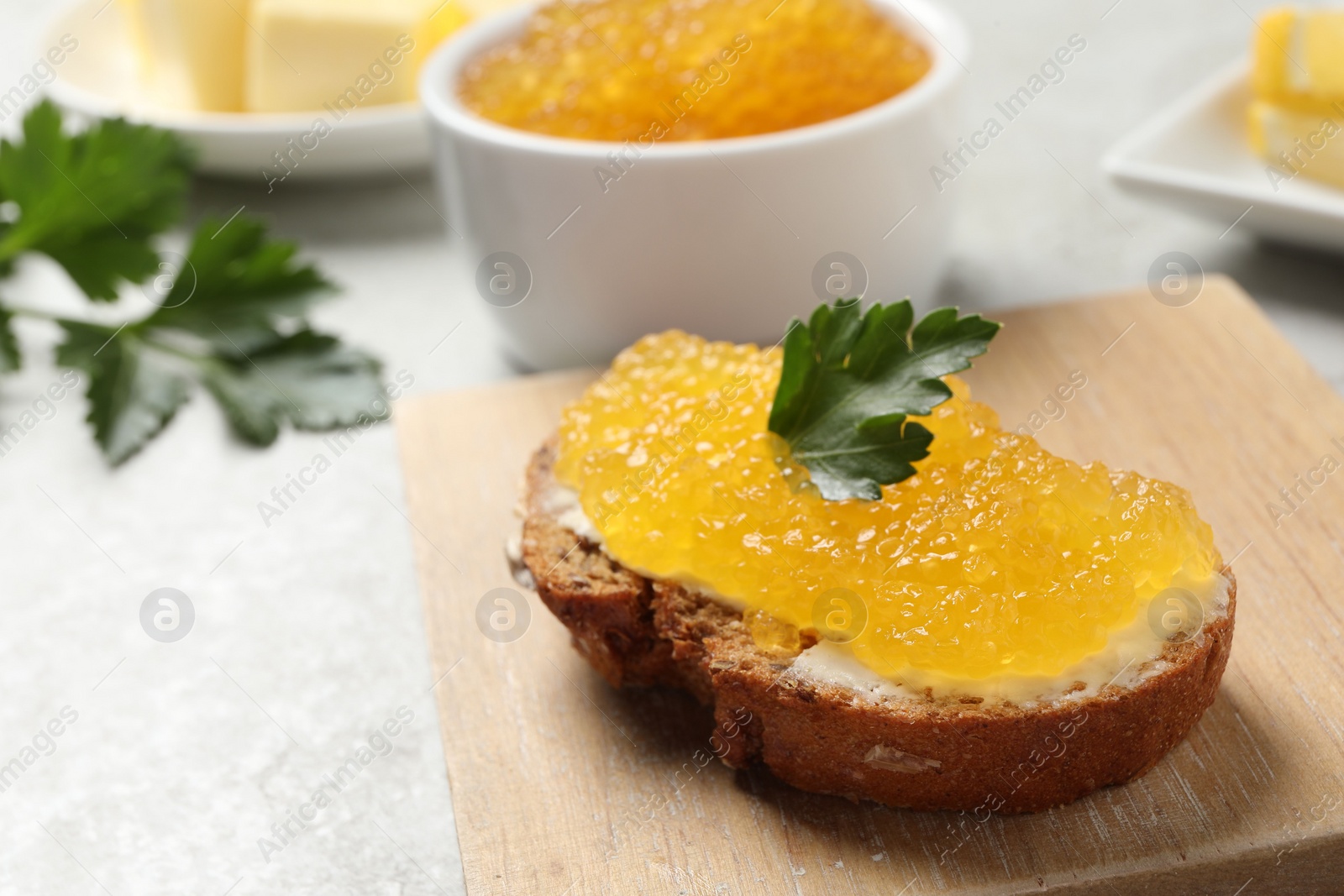 Photo of Tasty sandwich with pike caviar and parsley on light grey table, closeup