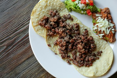 Photo of Plate with delicious tacos served on wooden table, top view. Space for text