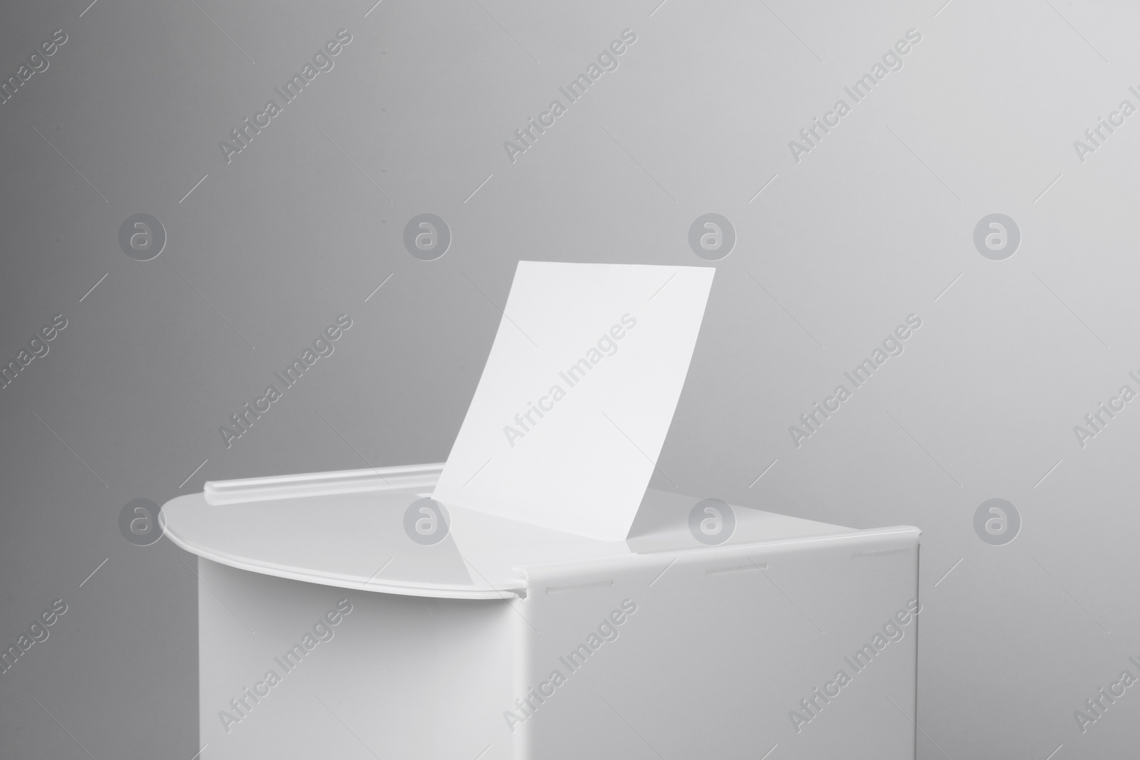 Photo of Ballot box with vote on light grey background, closeup. Election time