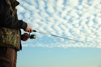 Photo of Fisherman with rod fishing under cloudy sky, closeup. Space for text