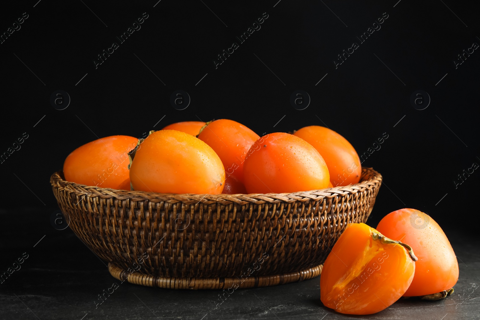 Photo of Delicious fresh persimmons on black slate table
