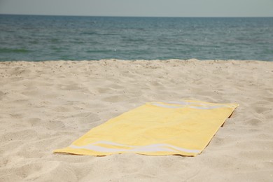 Photo of Yellow beach towel on sand near sea