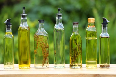 Many different cooking oils on wooden table against blurred green background