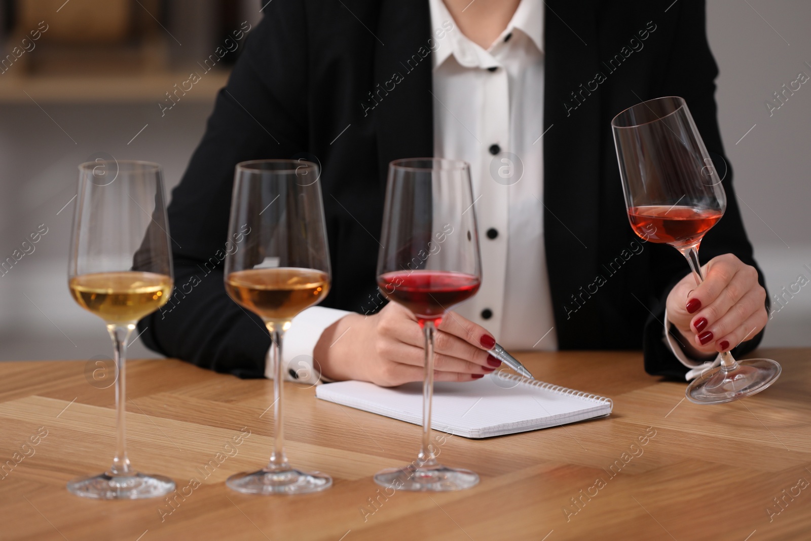 Photo of Sommelier tasting different sorts of wine at table indoors, closeup