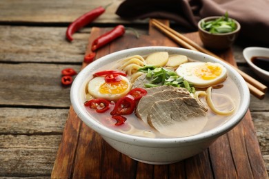 Delicious ramen in bowl on wooden table, closeup. Noodle soup