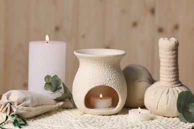 Photo of Different aromatherapy products, burning candles and eucalyptus leaves on table