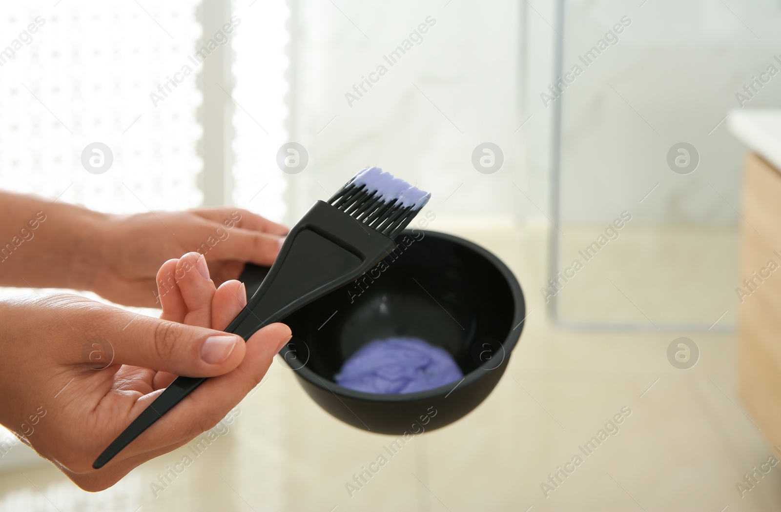 Photo of Woman preparing hair dye in bowl at home, closeup