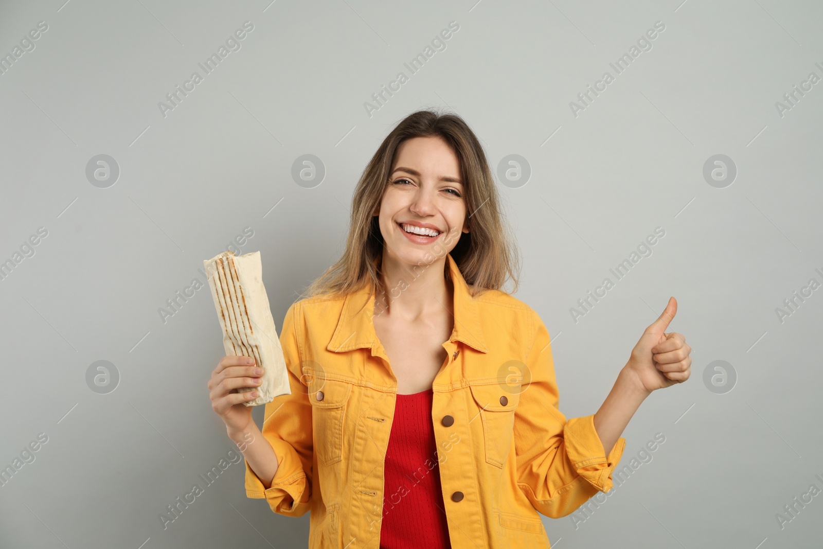 Photo of Young woman with delicious shawarma on grey background