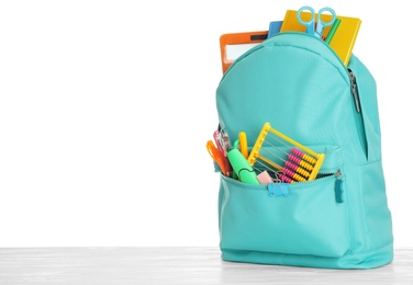 Photo of Stylish backpack with different school stationary on wooden table against white background