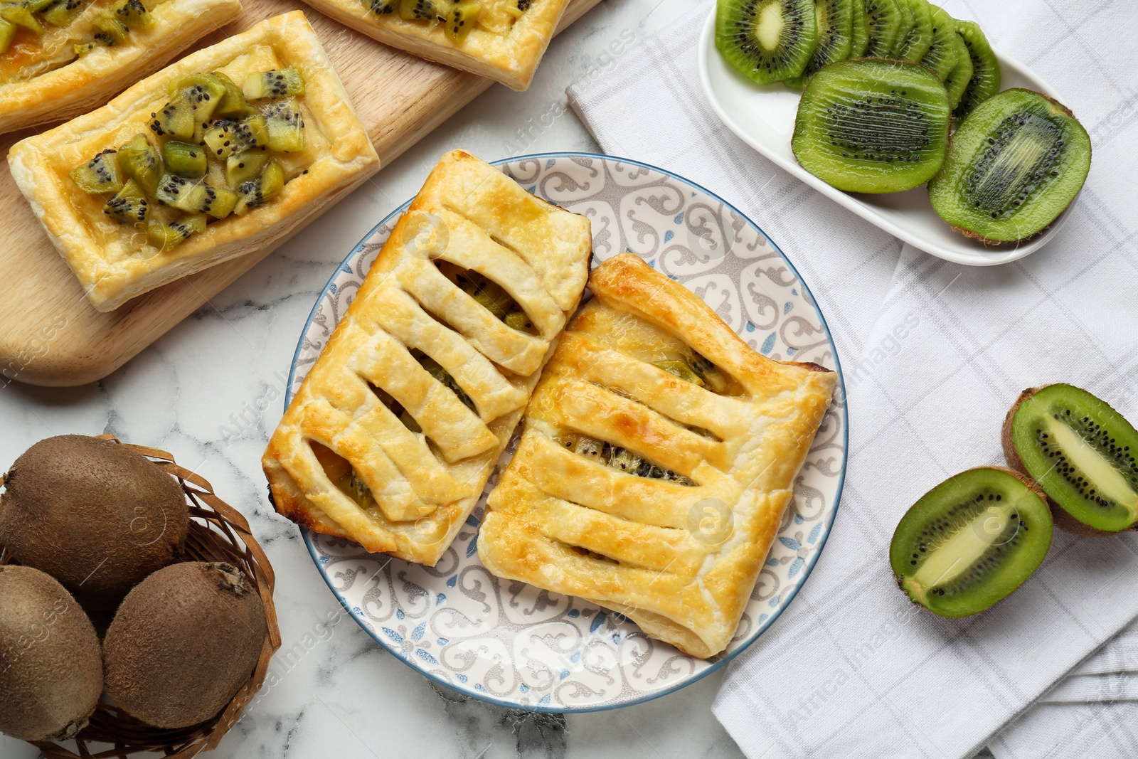 Photo of Fresh tasty puff pastry with kiwi on white marble table, flat lay