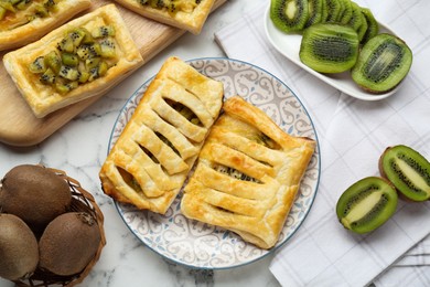 Fresh tasty puff pastry with kiwi on white marble table, flat lay
