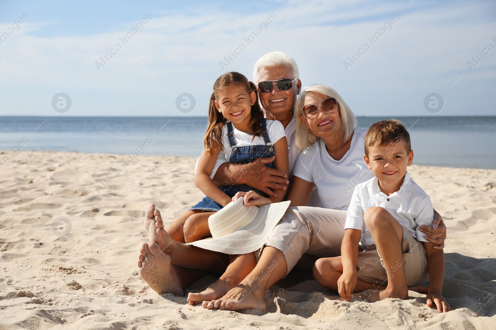 Photo of Cute little children with grandparents spending time together on sea beach