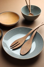 Photo of Stylish empty dishware and wooden cutlery on brown background