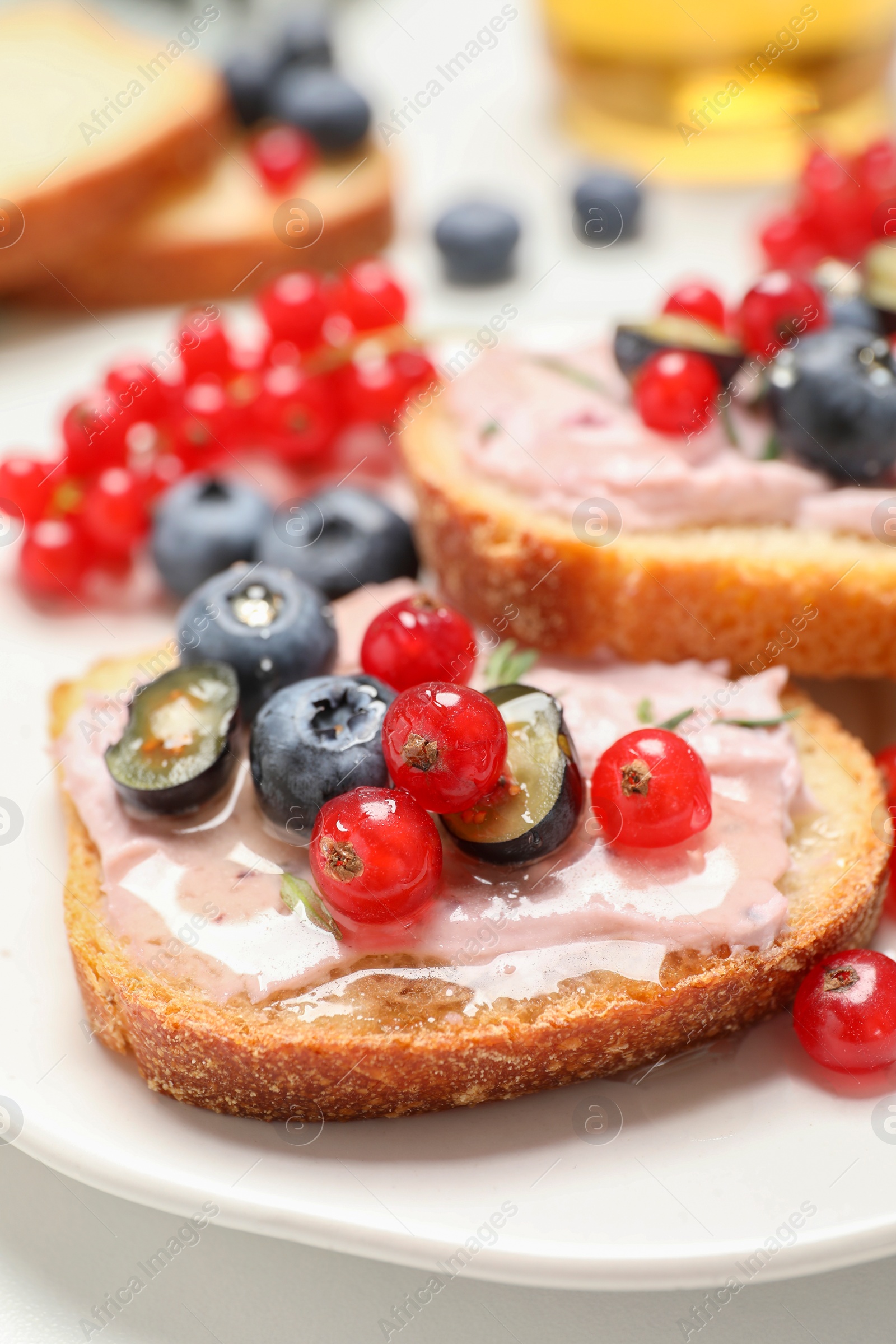 Photo of Tasty sandwiches with cream cheese, blueberries and red currants, closeup