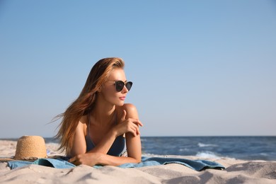 Photo of Attractive woman with sunglasses sunbathing on beach towel near sea, space for text