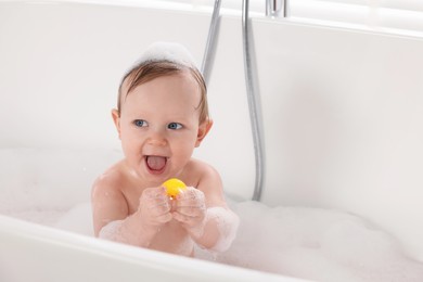 Photo of Cute little baby with toy bathing in tub at home