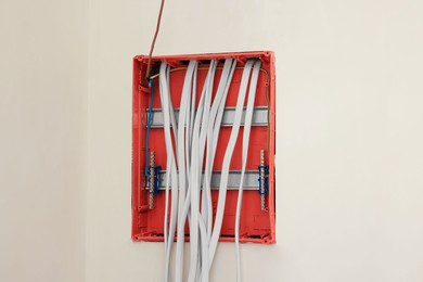 Photo of Switchboard with wires on beige wall indoors
