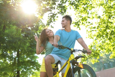 Photo of Young couple riding bicycle on city street, low angle view