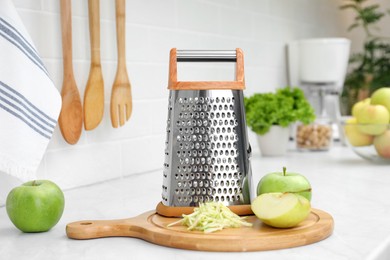 Photo of Grater and fresh ripe apples on kitchen counter