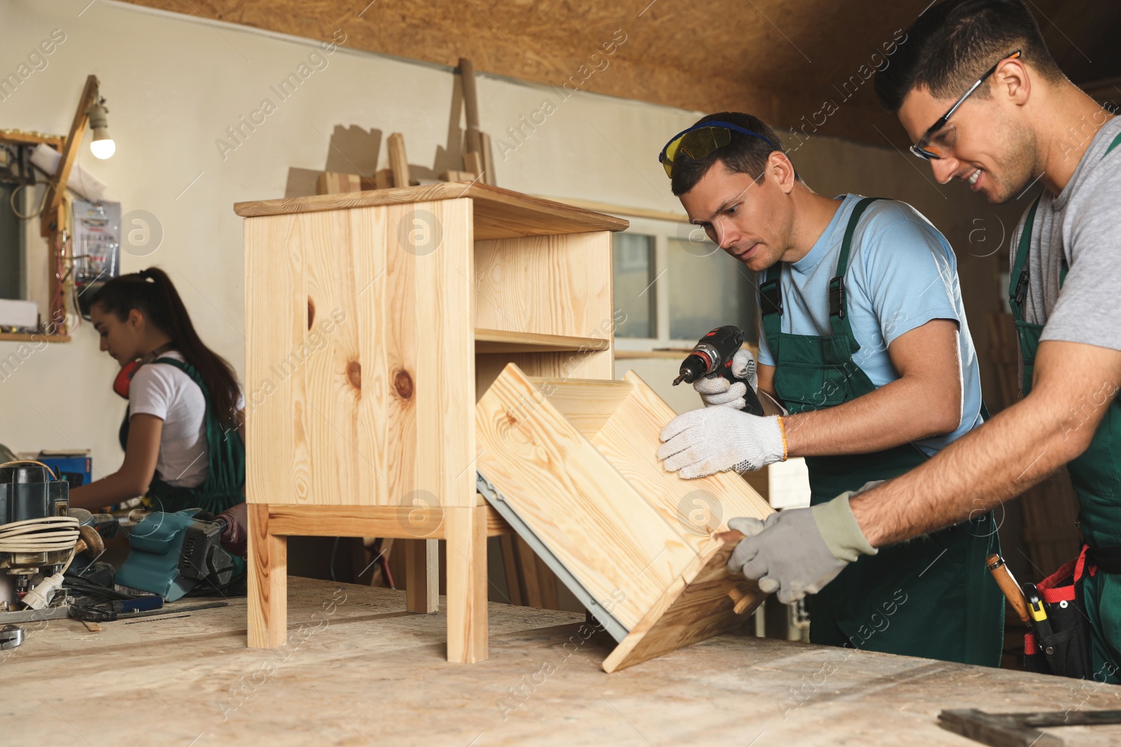 Photo of Professional carpenters assembling wooden cabinet in workshop