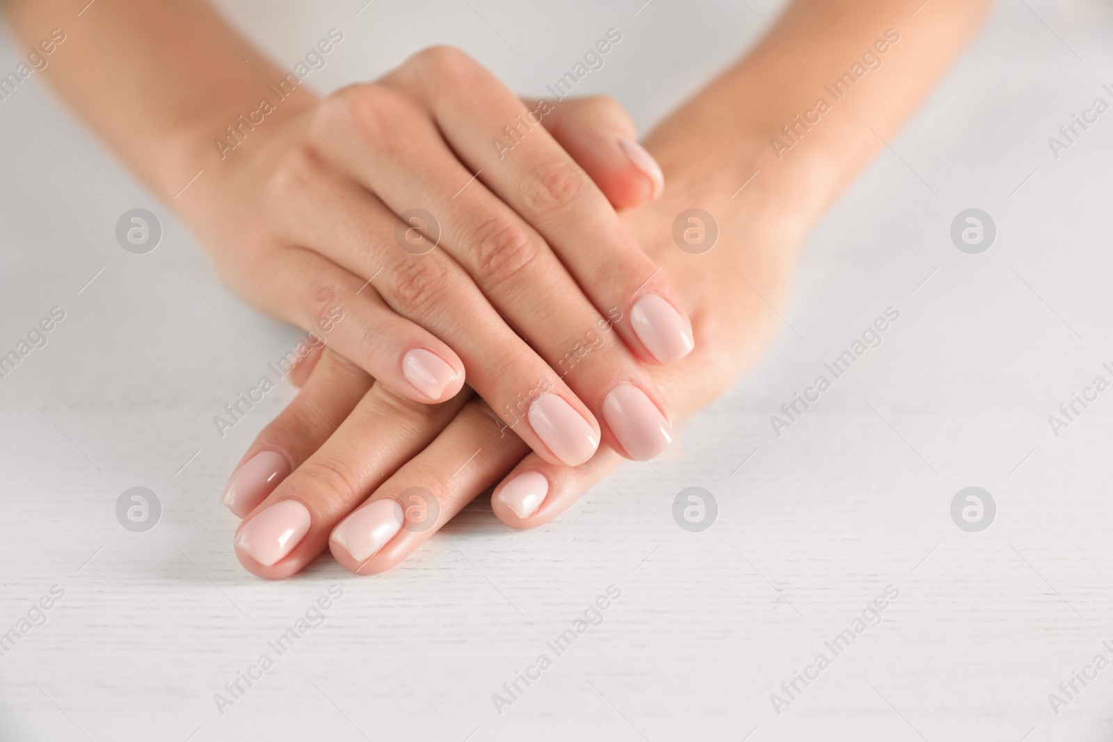 Photo of Closeup view of woman with smooth hands and manicure at table, space for text. Spa treatment