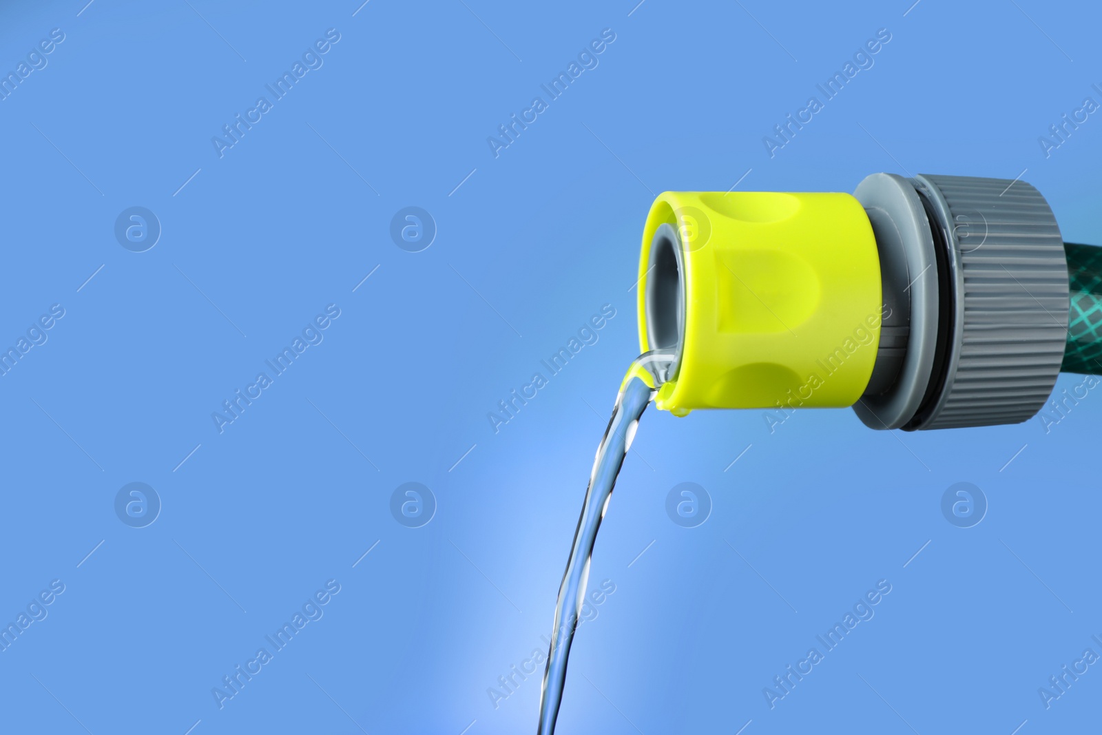 Photo of Water dripping from hose on blue background, closeup. Space for text