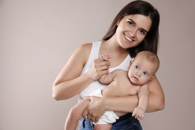 Beautiful mother with her cute baby on beige background