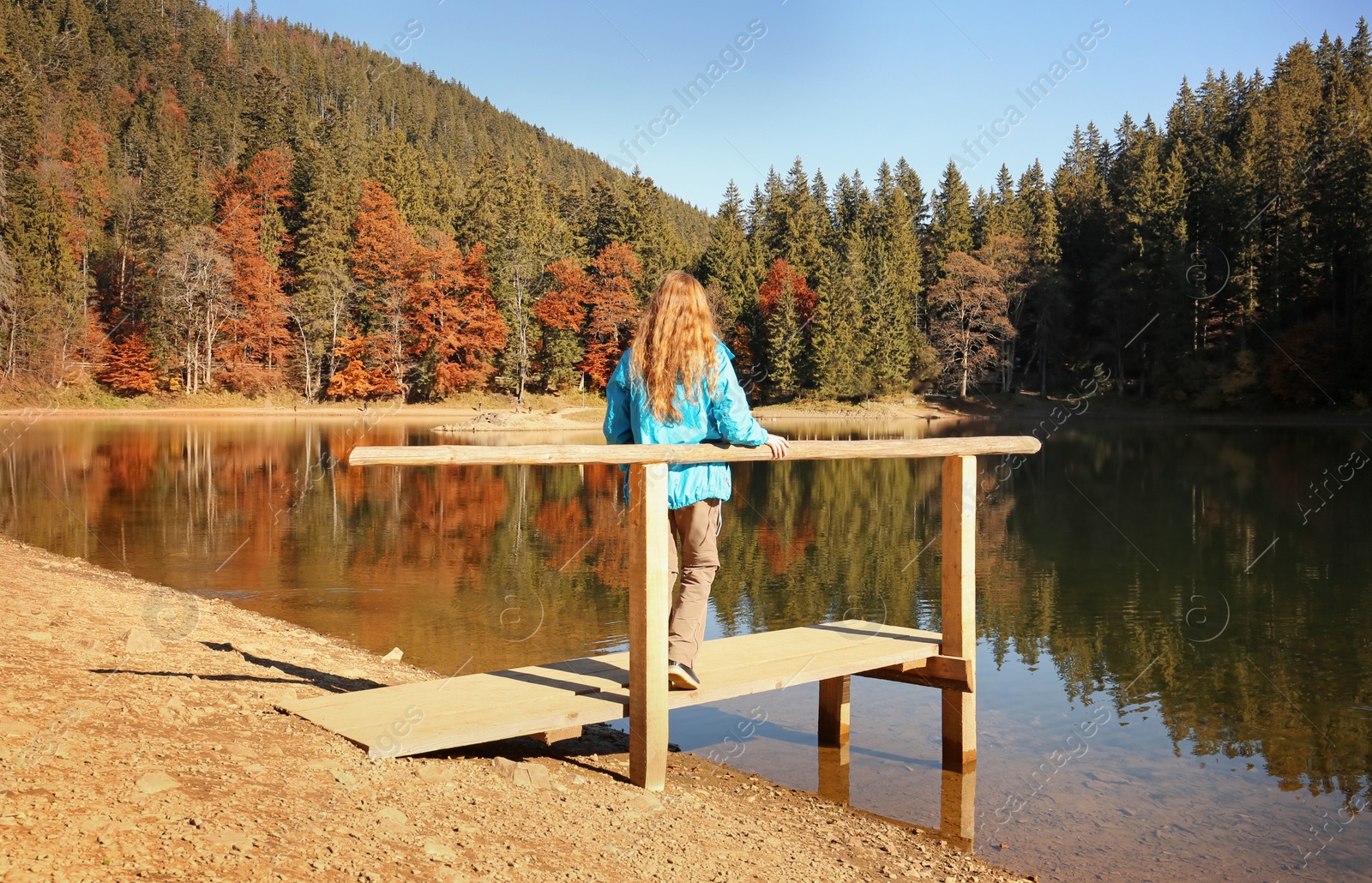 Photo of Woman enjoying view of autumn forest near lake