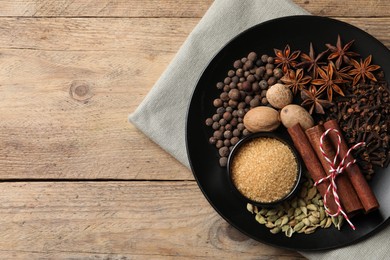 Dishware with different spices on wooden table, top view. Space for text