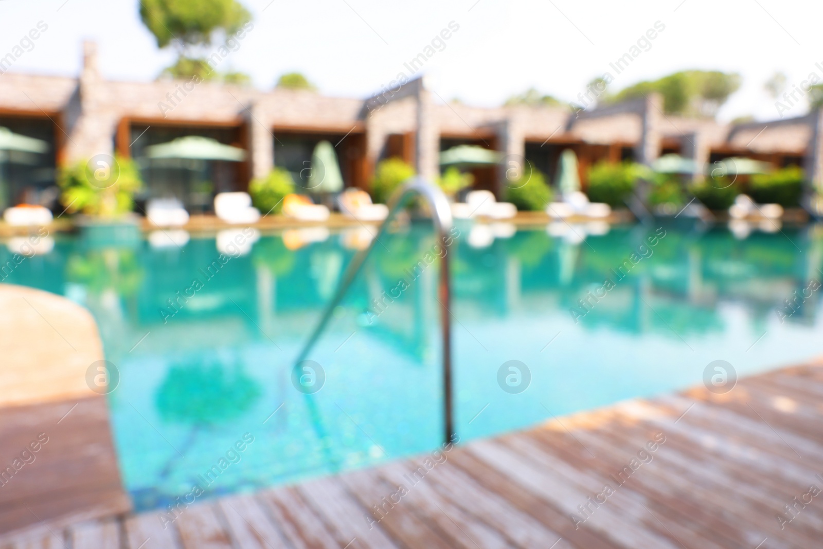 Photo of Outdoor swimming pool with wooden deck at resort, blurred view