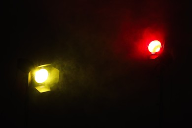 Photo of Bright colorful spotlights in darkness, space for text