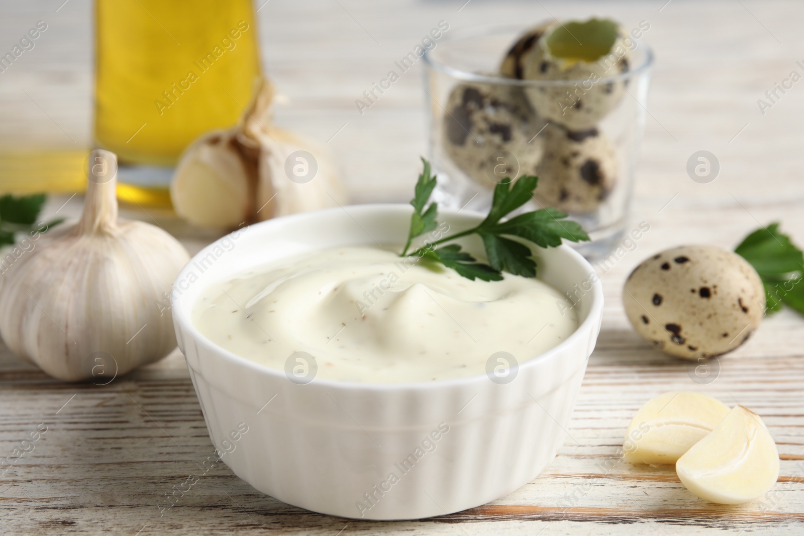 Photo of Composition with bowl of garlic sauce on wooden table