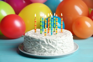 Delicious birthday cake with burning candles on table