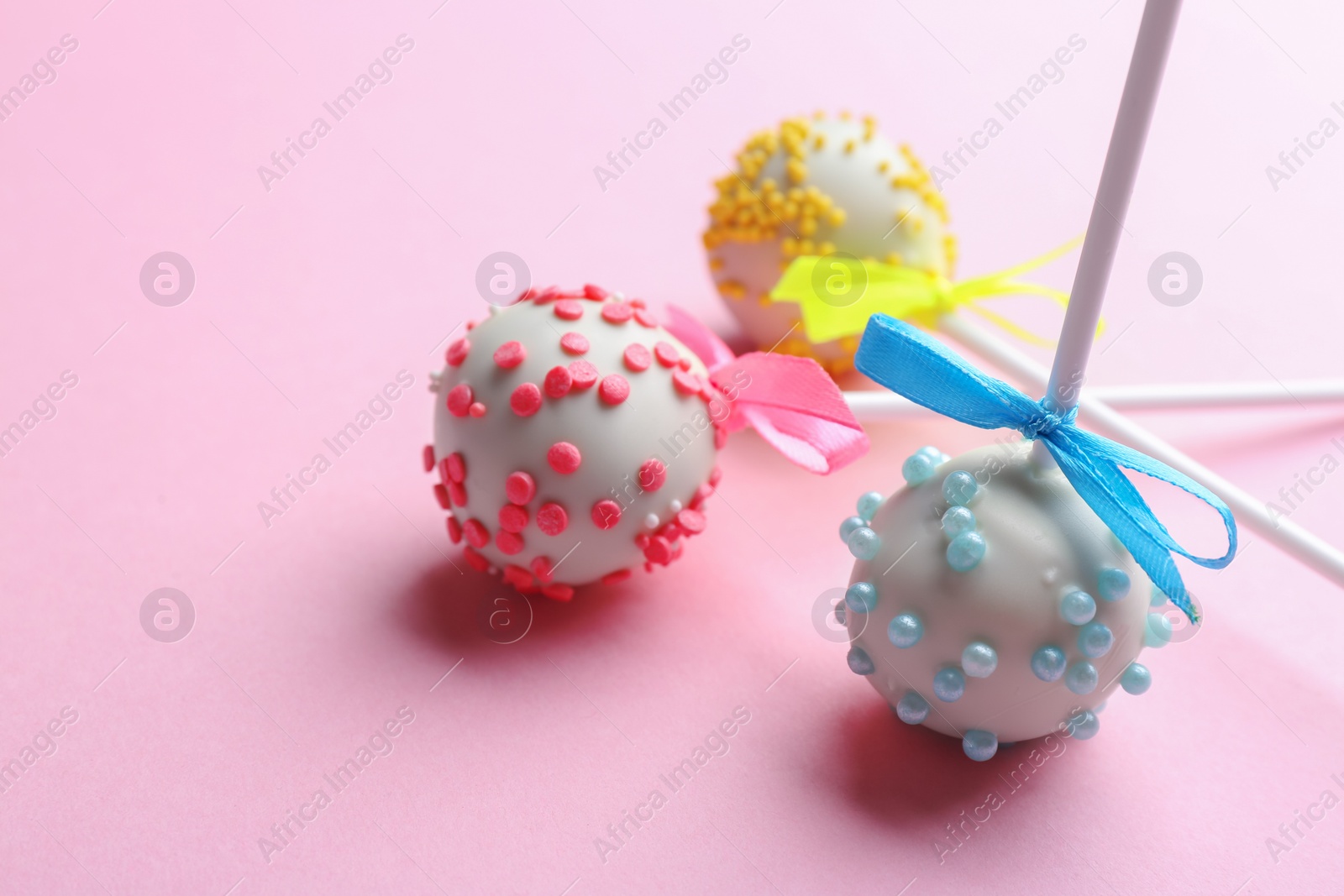 Photo of Different tasty cake pops on light pink background